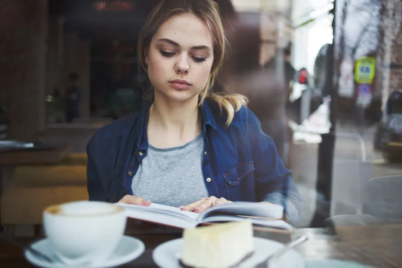 Женщина читает книгу в кафе, образ жизни во время отпуска, чашка кофе утром