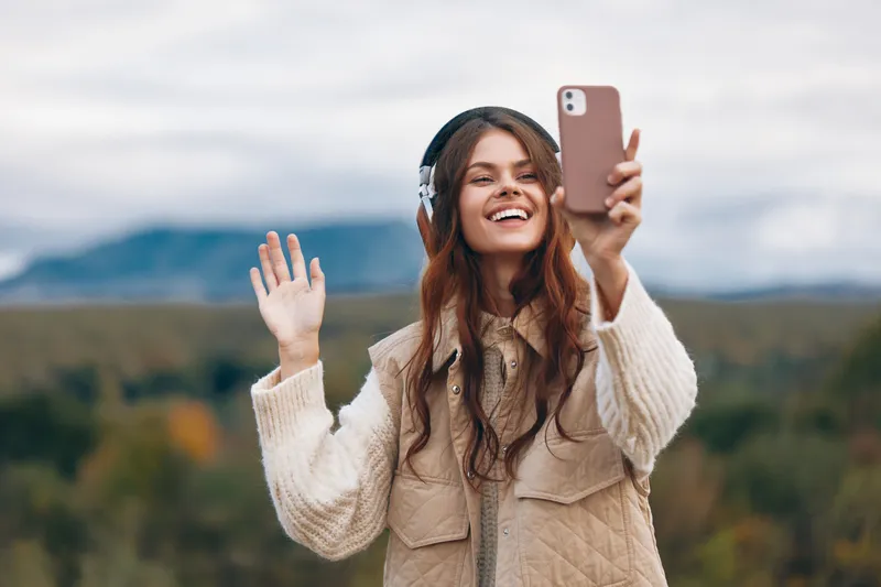 Женщина в горах наслаждается телефонным разговором на фоне свободы природы, делая селфи во время своего приключенческого похода
