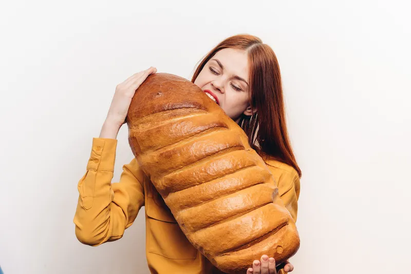 Женщина со свежей буханкой хлеба, голод, калории, мучной продукт