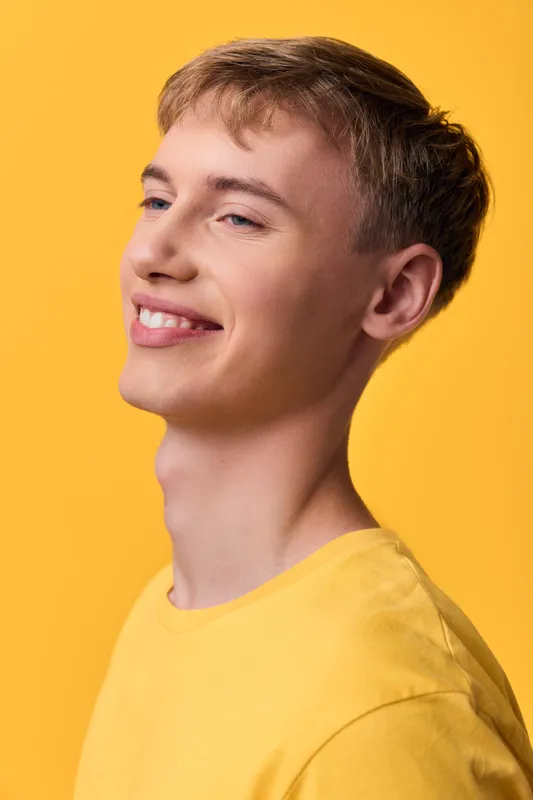 Smiling man wearing a yellow shirt against a bright yellow background, cheerful expression, casual pose, clean studio feel, friendly mood for lifestyle or advertising use.