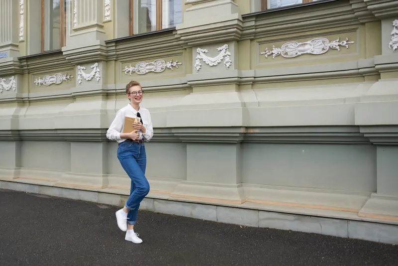 Студент в очках гуляет по городу с книгой, общаясь
