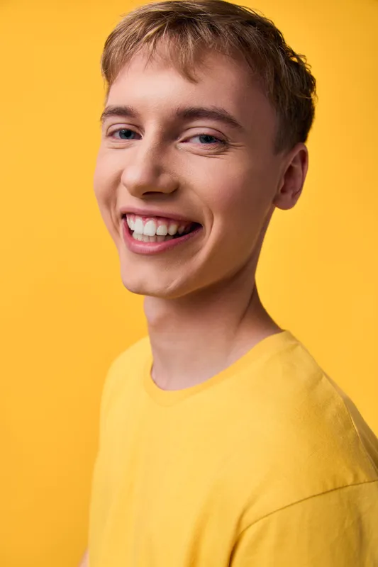 Smiling young man in a bright yellow shirt against a yellow background, conveying warmth, confidence and friendly vibes for lifestyle and branding projects
