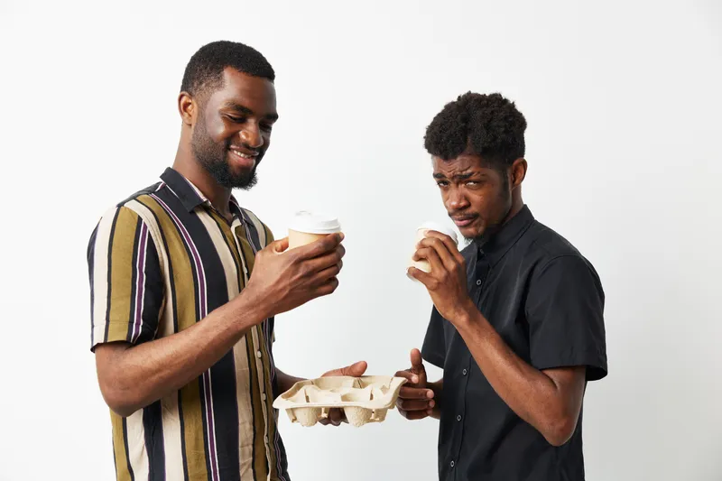 Cheerful black man enjoying coffee with a friend, vibrant colors, modern style, friendly atmosphere. Perfect capture of joy and connection in everyday moments.