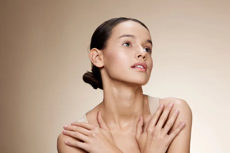 Elegant portrait of a young woman with a natural look, showcasing beauty and self care with a serene expression against a soft beige background
