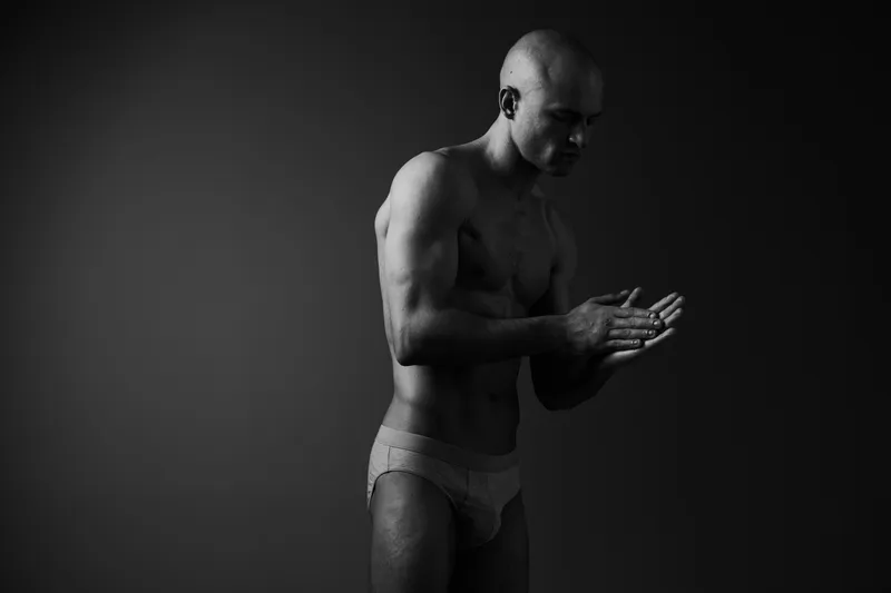 Black and white image of a man posing thoughtfully, showcasing his physique. Emotional and artistic, ideal for fitness and health concepts.