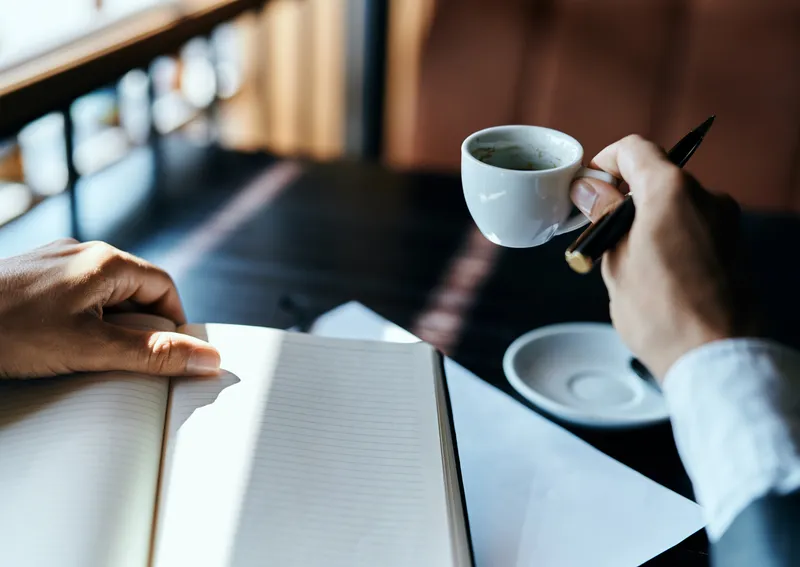 Деловая женщина в кафе: на столе книга, документы и чашка кофе