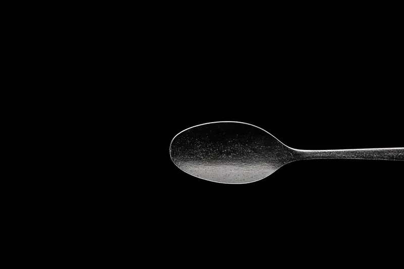 Искусно изготовленная серебряная ложка, изолированная на чёрном фоне, демонстрирующая её отражающую поверхность и плавные изгибы, идеально подходит для кулинарных концепций и концепций сервировки…
