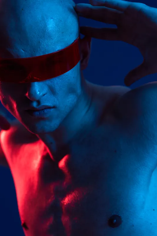A striking image of a man with futuristic red sunglasses, showcasing a bold expression and artistic lighting. The composition highlights the unique features and colors.