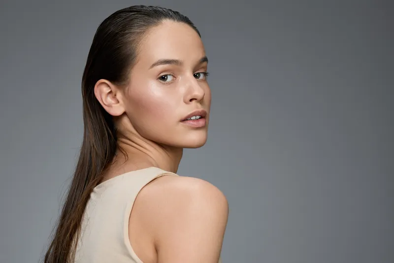 Elegant model showcasing natural beauty against a grey backdrop, exuding confidence and subtle grace, perfect for health and beauty concepts