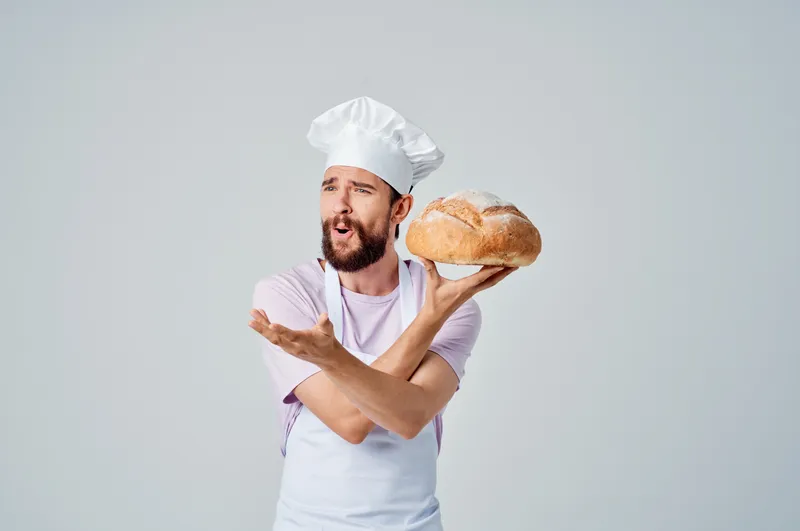 Бородатый мужчина в фартуке занимается приготовлением еды на кухне ресторана