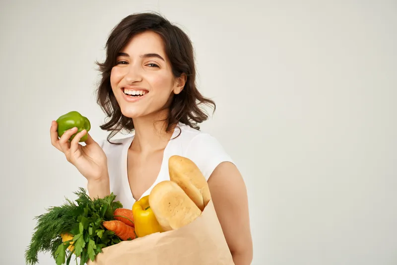 Весёлая брюнетка с пакетом продуктов для доставки из супермаркета