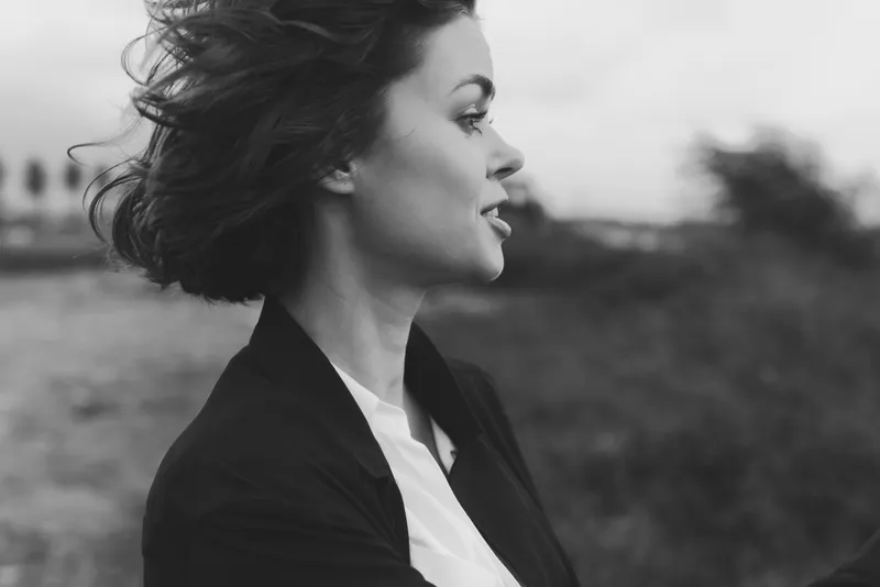 Profile of a woman in an outdoor setting, wind in her hair, captured in monochrome for moody elegance and thoughtful mood, suitable for lifestyle, fashion, or creative editorial use