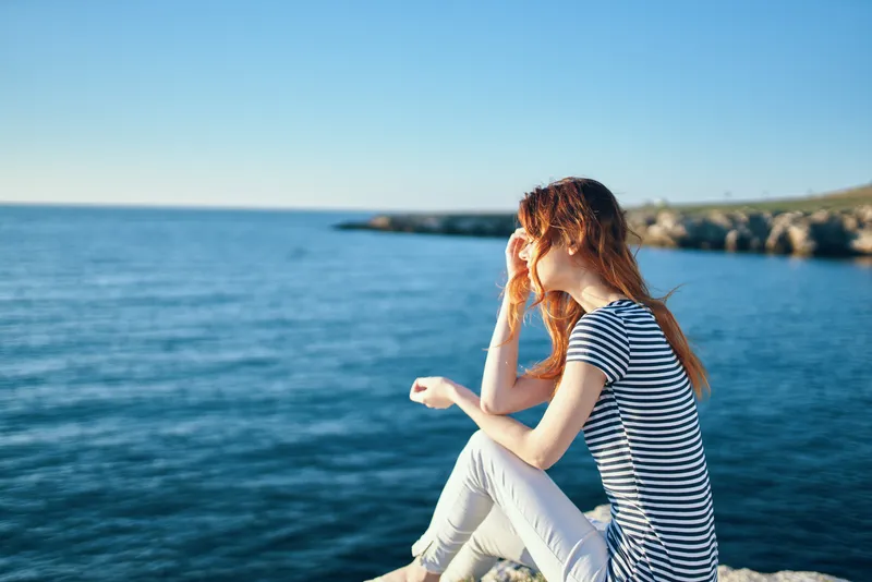 Женщина на скале у моря в горах, закат, лето