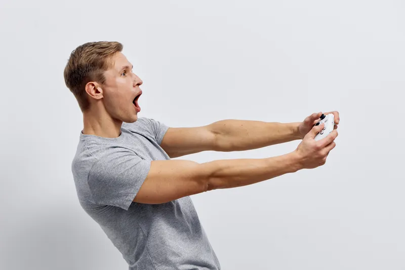 Young excited man playing video games with wireless controller casual clothing on white background digital entertainment cyberspace concept