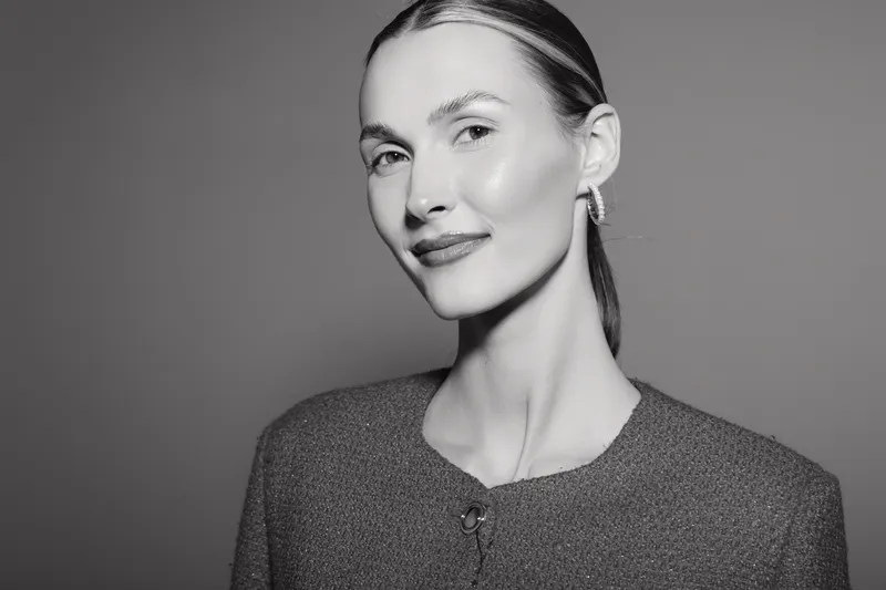 Portrait of a young Caucasian woman with fair skin smiling confidently in studio lighting. Concept of beauty, elegance, and natural expression.