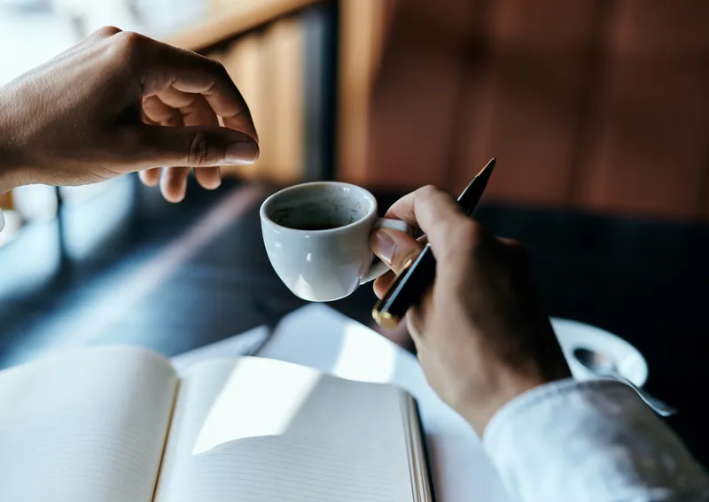 Бизнесвумен в кафе с книгой на столе, документами и чашкой кофе — рабочий образ жизни