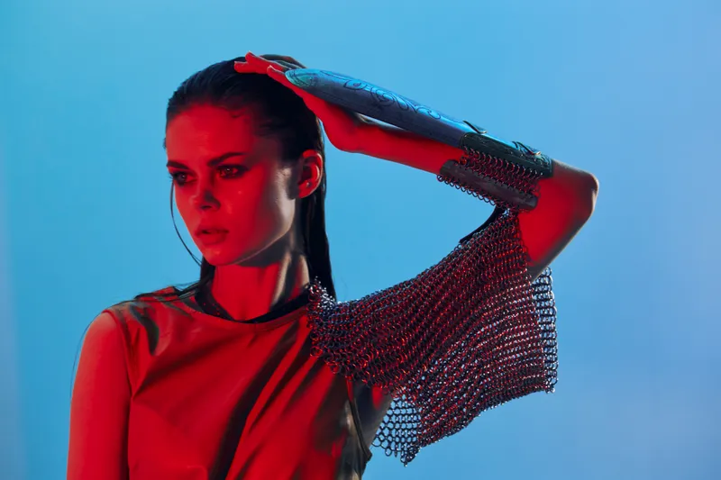 Привлекательная женщина в платье с рукой в доспехах и кольчуге на изолированном фоне