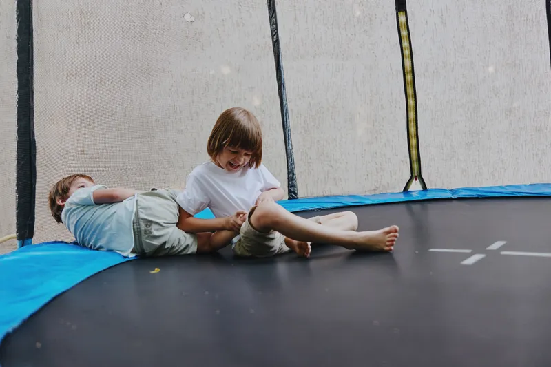 Happy children playing on a trampoline, enjoying laughter and gaining joy through playful activities. Their cheerful expressions reflect the innocence of childhood.