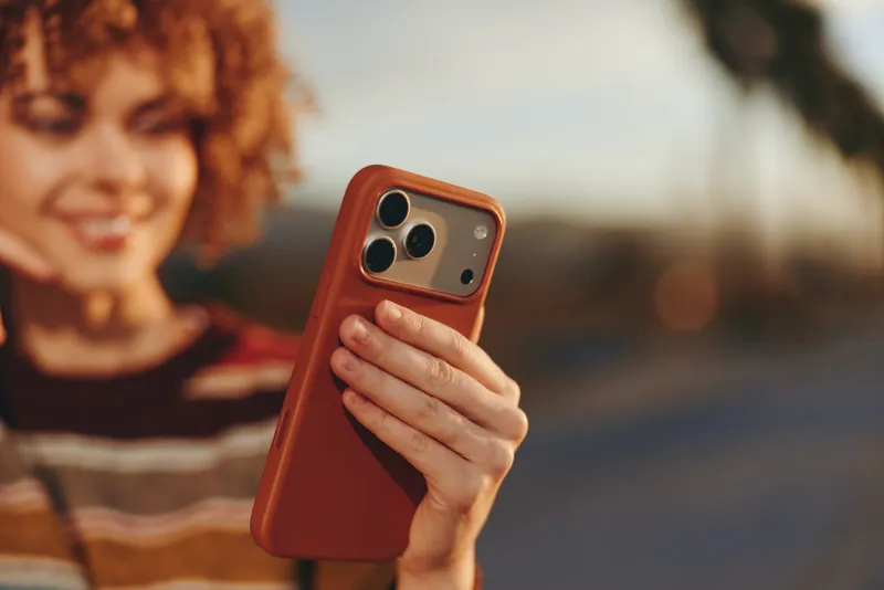 Woman with smartphone in hand, lifestyle outdoors at sunset, communication and technology concept, close portrait framing, blurred smiling woman in background, warm travel mood