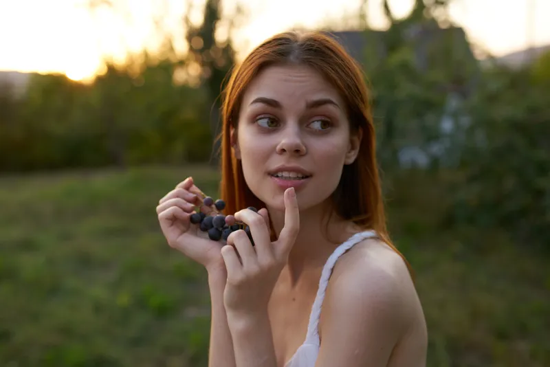 Женщина ест виноград на природе, да, органический