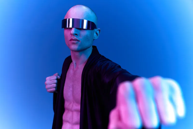 Confident man in stylish futuristic sunglasses showing a strong pose in neon light, emphasizing a modern and bold aesthetic.