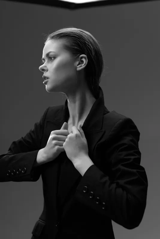 Black and white portrait of a serious woman in a blazer with focused expression and studio lighting.