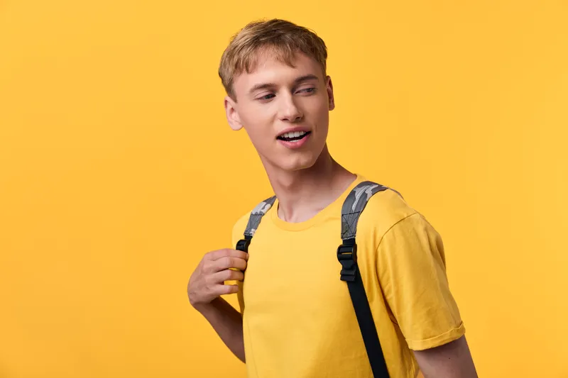 Man with a backpack against a vibrant yellow backdrop, casual tshirt style, youthful energy and street fashion, ready for everyday adventures and new experiences