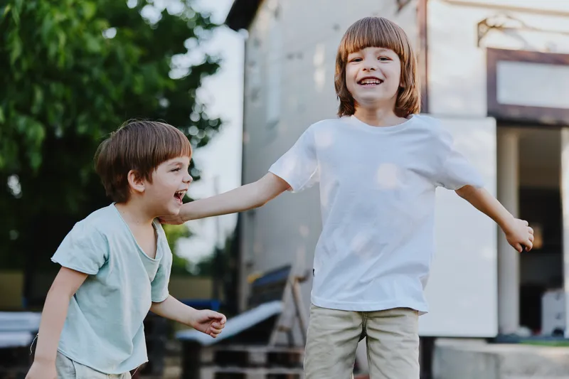 Joyful children playing outdoors, expressing happiness and laughter in the sunlit backyard, showcasing their playful nature. Perfect for family themes.