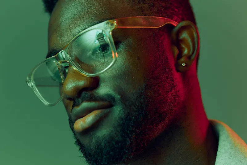 Stylish male model with glasses showcasing modern fashion and vibrant colors against a soft gradient background, exuding confidence and trendiness
