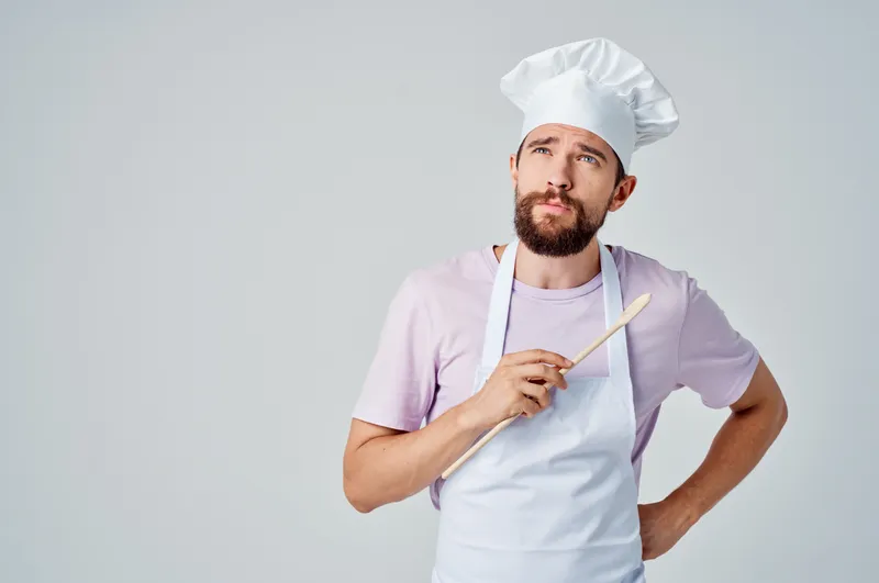 Эмоциональный шеф-повар работает на кухне, занимаясь приготовлением блюд и обслуживанием