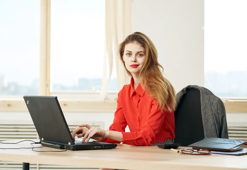Деловая женщина работает за столом в офисе с ноутбуком, секретарь