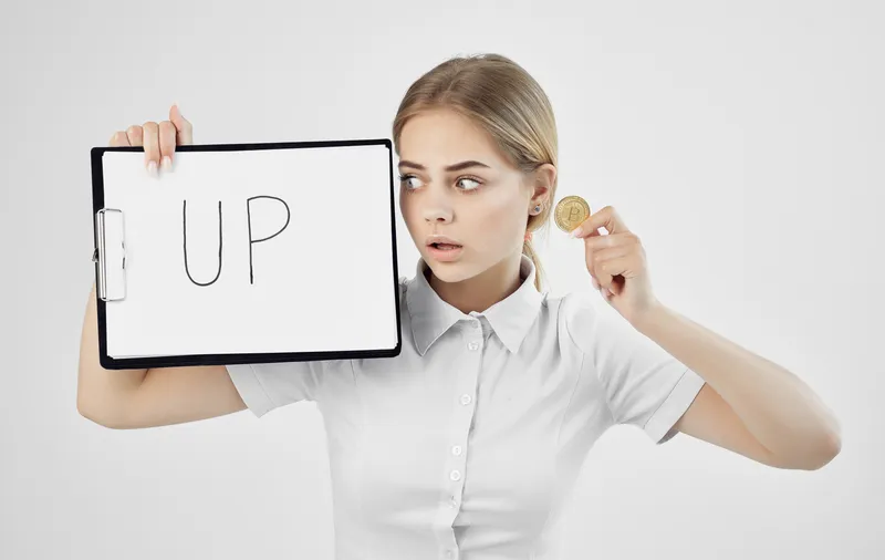 Весёлая женщина в белой рубашке держит папку с надписью «Upward Cryptocurrency Bitcoin Internet Finland»