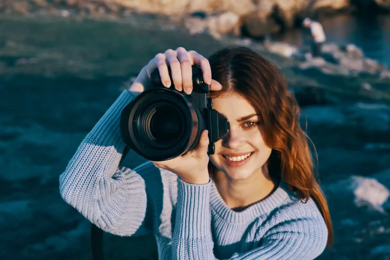 Жизнерадостная женщина-туристка с фотоаппаратом на природе, в горах, для профессионалов