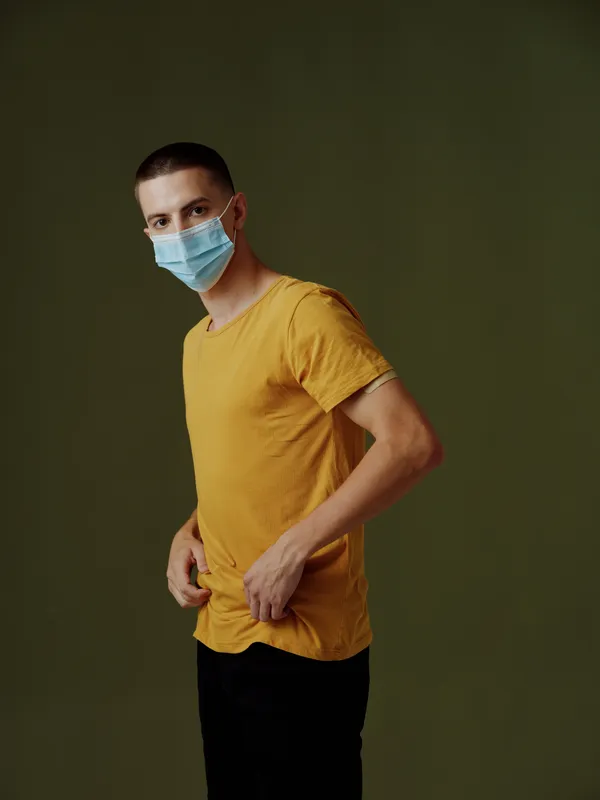 Мужчина в медицинской маске с пластырем на плече, вакцинный паспорт COVID-19