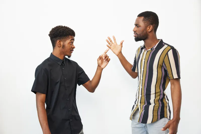 Two African American men engaged in a lively conversation, displaying dynamic expressions and gestures. The image captures the essence of friendship and connection.