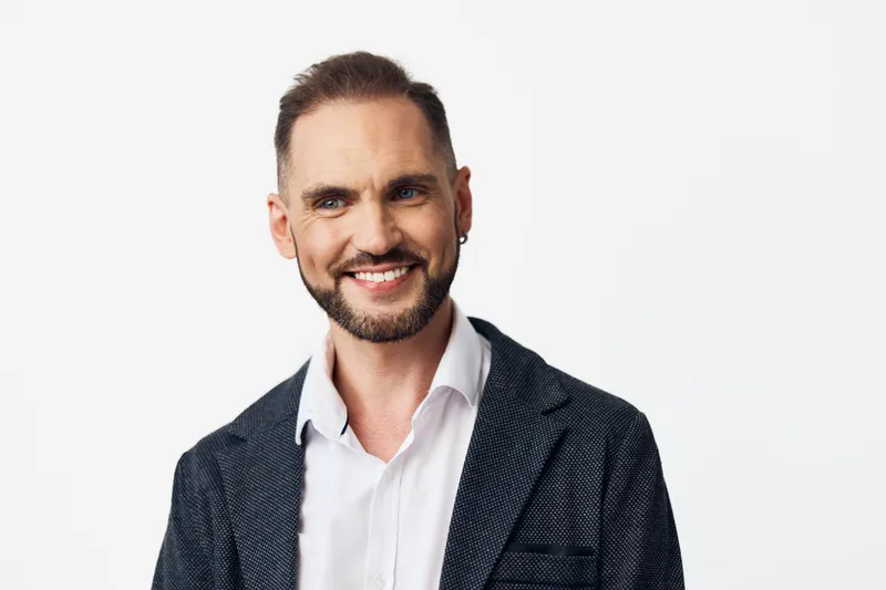 A confident business professional smiles softly against an isolated light color backdrop, projecting competence and approachability for corporate branding, leadership, and executive lifestyle visuals.