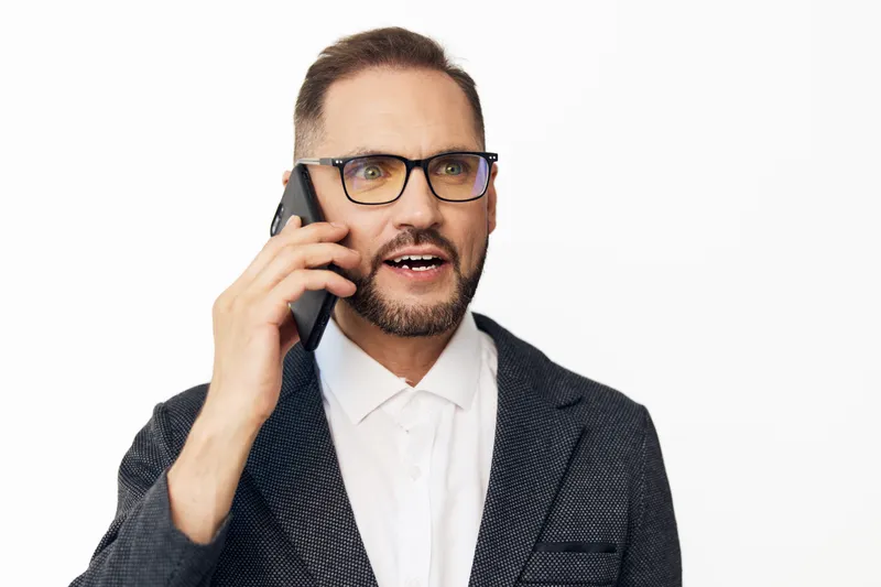 A professional man on a call, exuding confidence and focus against an isolated colorful background, wearing a smart blazer and white shirt, sharing key business insights.