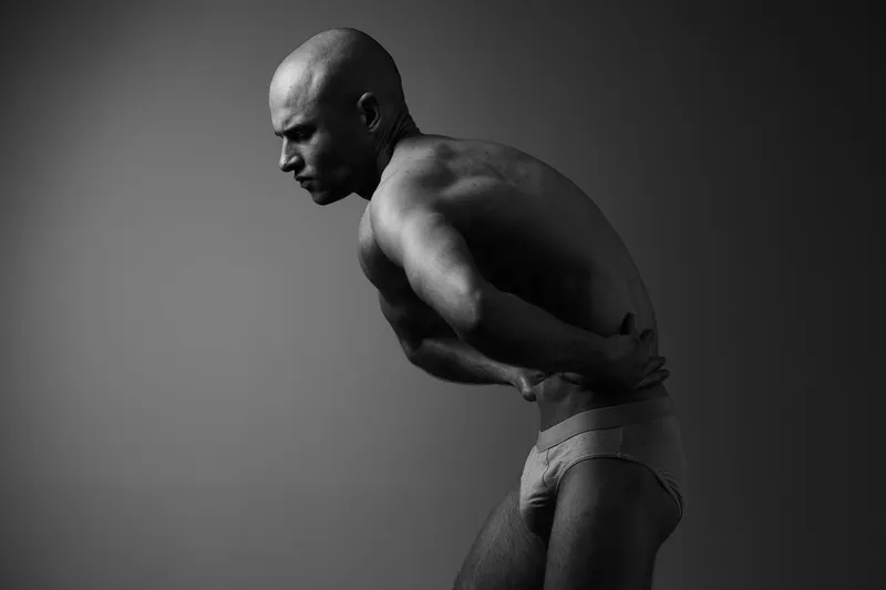 A black and white image of a man in a contemplative pose, showcasing emotion and depth. The lighting highlights his features and adds a dramatic effect.