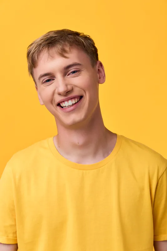 Smile, yellow, man, young, cheerful, lifestyle, fashion, happy, warmth, upbeat in a bright studio shot featuring a smiling man in a yellow t shirt against a vivid yellow backdrop, conveying energy,