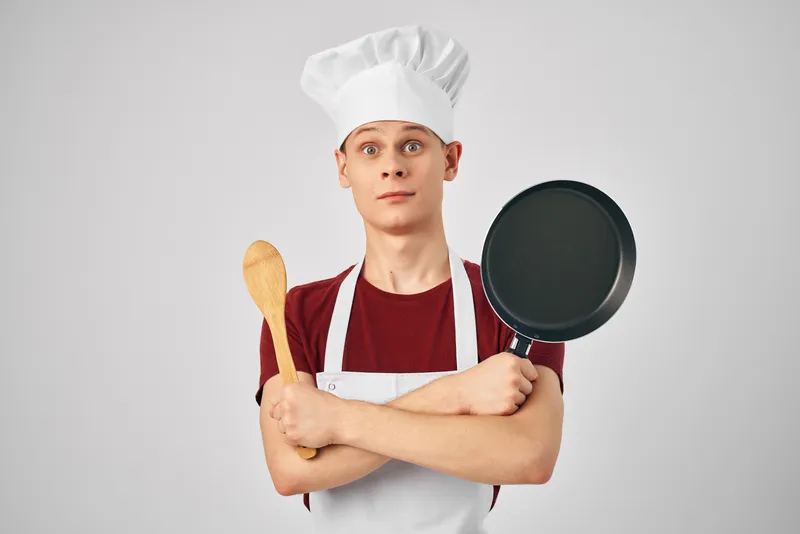 Повар-мужчина с кухонной утварью занимается приготовлением блюд в ресторане
