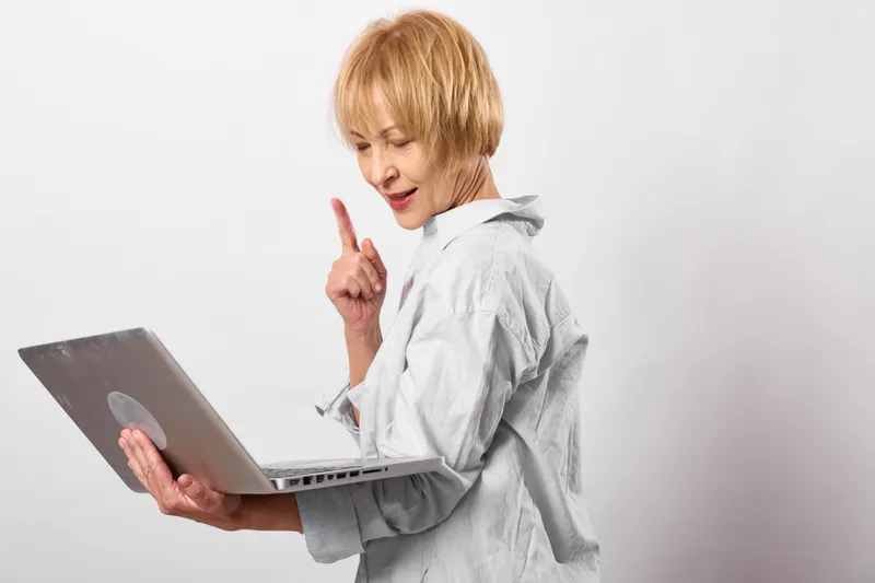 Woman at laptop in studio, technology concept for working and communication, remote office professional. She points and focuses, using a notebook computer.