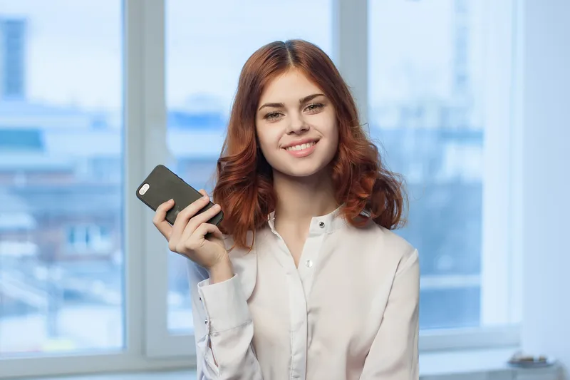 Симпатичная женщина в рубашке с телефоном в руке, общение, офис, профессионализм