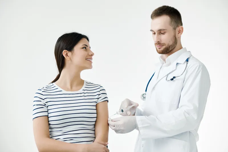 Улыбающаяся женщина в больнице делает вакцину от коронавируса