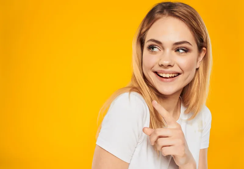 Счастливая блондинка показывает рукой в сторону, крупный план с обрезанным видом