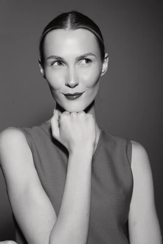 Portrait of a thoughtful Caucasian woman with fair skin and slicked-back hair wearing a sleeveless top. Concept of contemplation, elegance, and minimalistic style in black and white.