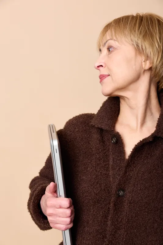 Elderly woman with smartphone, communication technology, portrait profile, beige indoors lifestyle concept, holding phone in hand, calm expression, soft minimal studio light