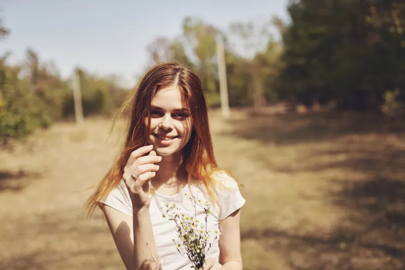 Счастливая женщина в поле с букетом белых цветов на природе