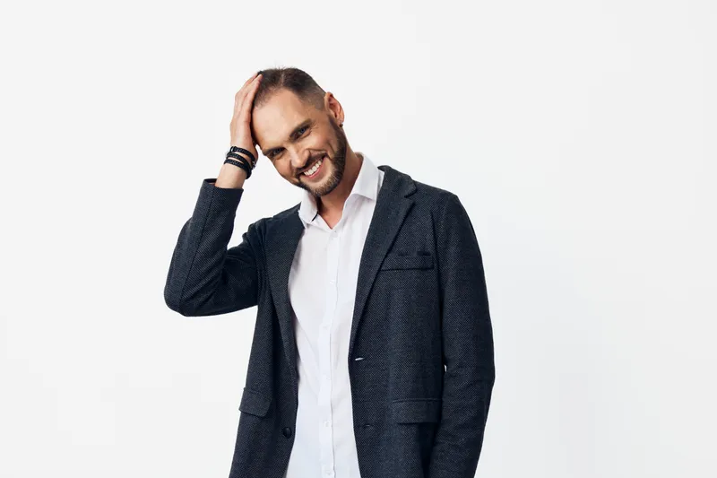 A business professional man stands against an isolated colored background, calm and confident, projecting focus, poise, and readiness for leadership in a corporate setting.