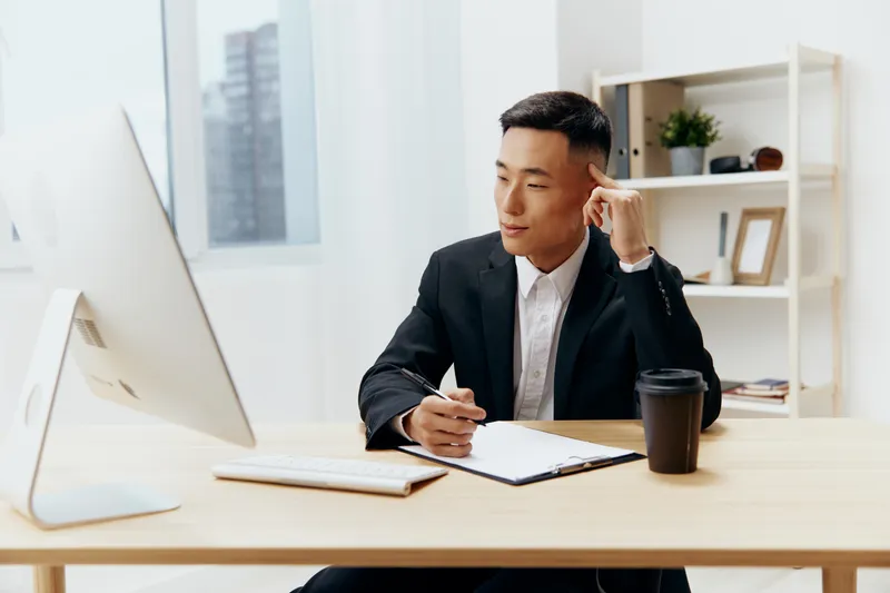 Менеджер работает за компьютером, рядом стоит чашка кофе, на лице — эмоции