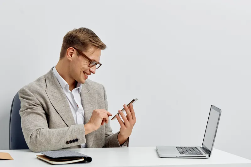 smiling man working with smartphone laptop cyber security digital nomad glasses casual jacket white background concept